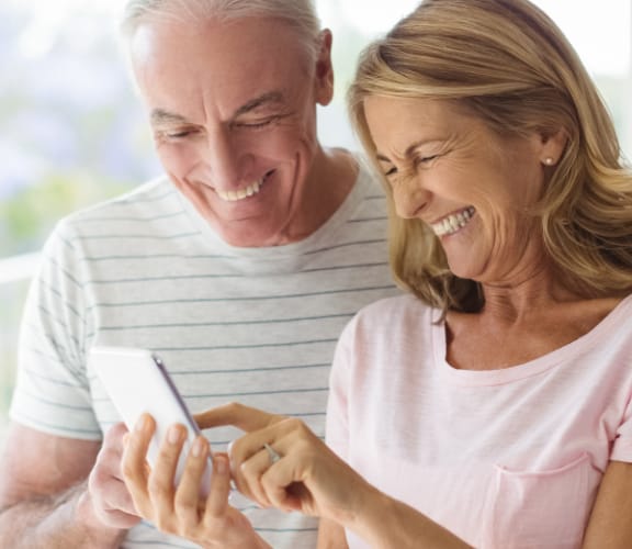 Mature couple standing near each other and looking down at a phone that the woman is holding