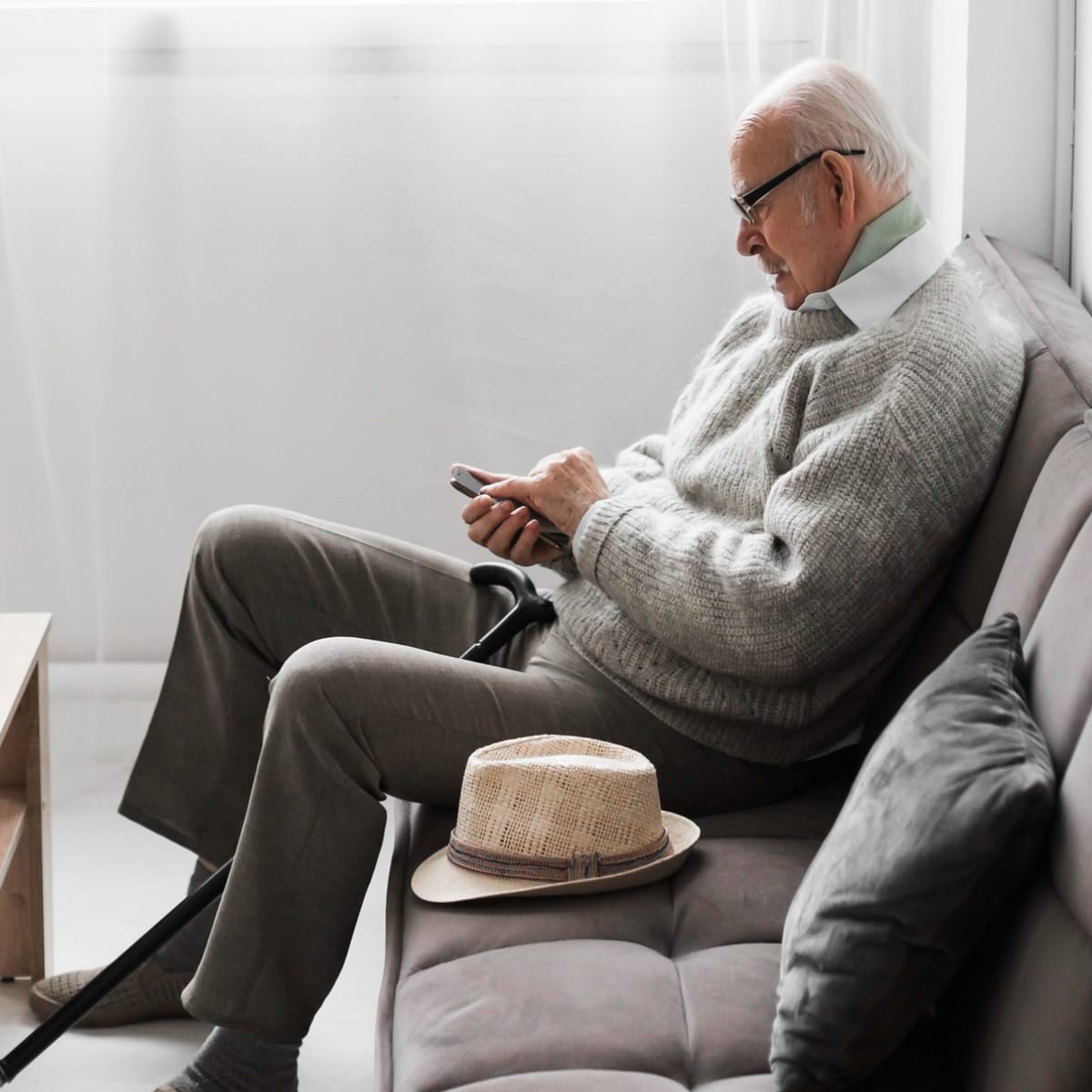 Older mal sitting on couch looking down at his phone