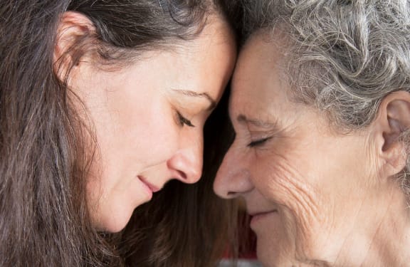 Older woman and her daughter touching foreheads with their eyes closed