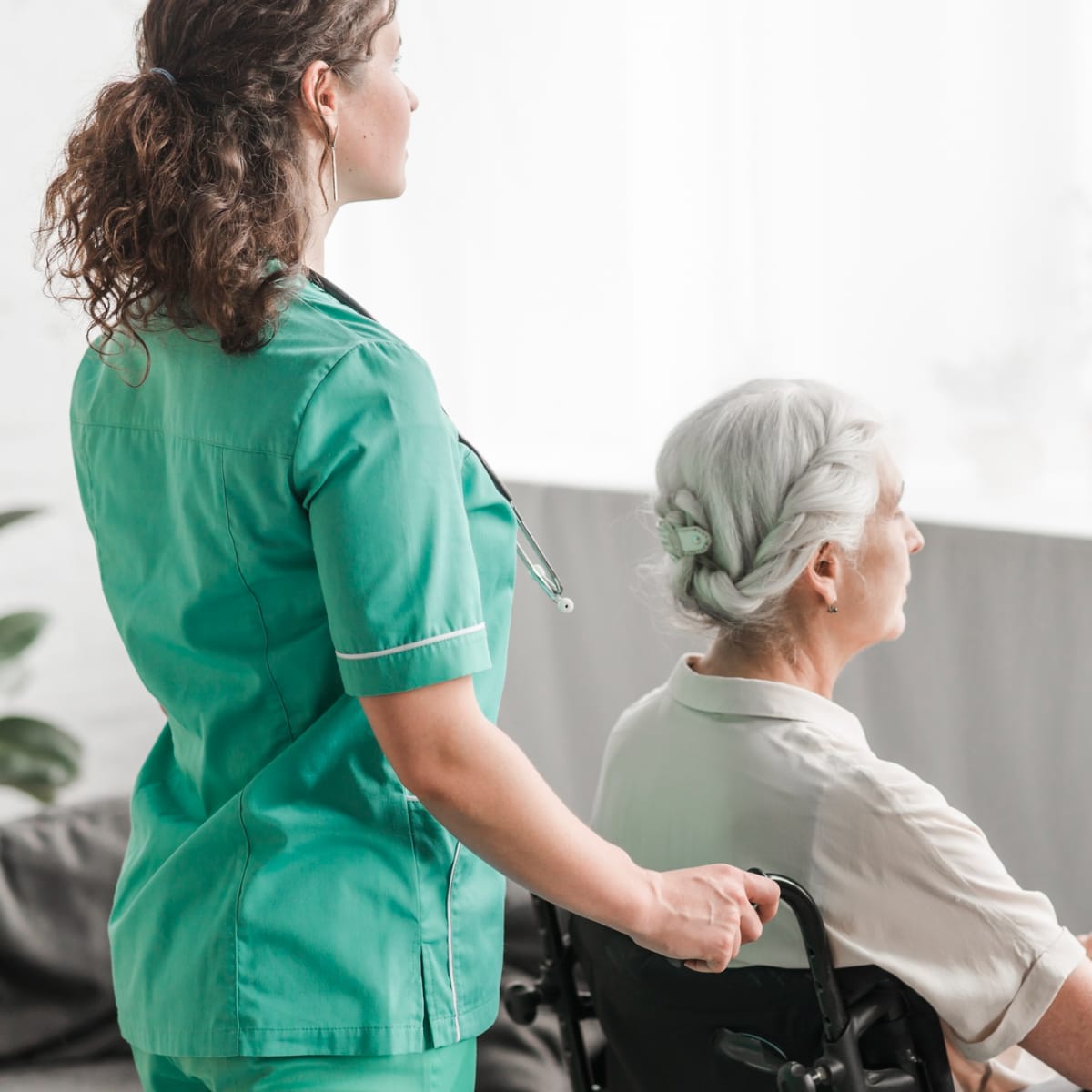 Caregiver pushing an elderly woman in a wheelchair